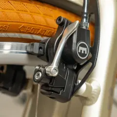 Nahaufnahme einer Fahrradbremse mit orangefarbenem Reifen und Felge.