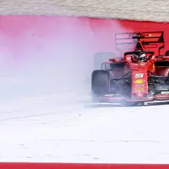 Ein roter Formel 1 Ferrari mit der Startnummer 5 bremst stark ab und erzeugt viel Rauch. Ein Formel 1 Auto verbraucht enorm viel Kraftstoff.