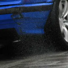 Blauer Sportwagen mit drehendem Rad, das Wasser aufwirbelt. Die elektronische Differenzialsperre sorgt für Grip.