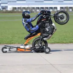Motorradfahrer übt einen Wheelie auf einem Trainingsständer.