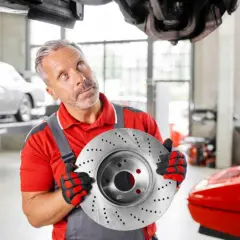 Mechaniker hält Bremsscheibe, gute febi bremsen erfahrung. Auto in Werkstatt.