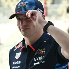 Max Verstappen in Red Bull Racing Kappe und Polo-Shirt, die Hand am Schirm.