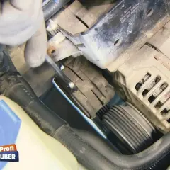 Hand mit Werkzeug am Keilrippenriemen eines Autos.