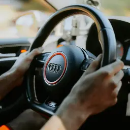 Hände am Lenkrad eines Audis, Tacho zeigt 61 km/h. Die Fahrt beginnt.