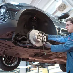 Mechaniker arbeitet am Bremssystem eines Autos. Hoffentlich quietschen die neuen Bremsen nicht.