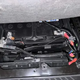 Ford Transit Batterie wechseln: Neue Batterie mit Kabeln und Sicherungskasten unter dem Sitz.