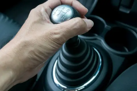 Hand schaltet mit der auto kupplung den Gang.