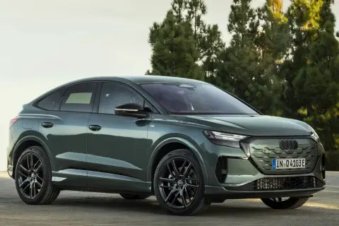 Der **Audi Q4 Facelift** in elegantem Grün steht vor Bäumen. Sein sportliches Design mit coupéhafter Dachlinie und markanten Felgen macht ihn zum Hingucker.
