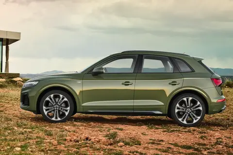 Grüner Audi Q5 mit 3,0 l V6 Diesel-Motorisierung steht auf einem felsigen Untergrund vor einem modernen Gebäude.