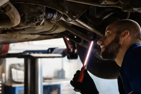 Mechaniker prüft das Fahrwerk eines Autos, um sicherzustellen, dass das audi s tronic Getriebe einwandfrei funktioniert.