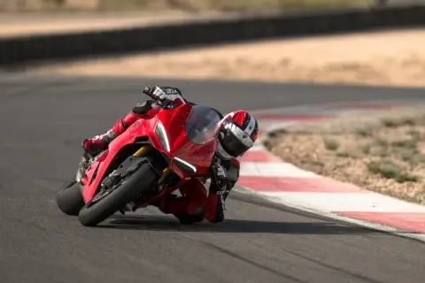 Ein Rennfahrer auf einer roten Ducati Panigale V2 lehnt sich tief in eine Kurve auf einer Rennstrecke.
