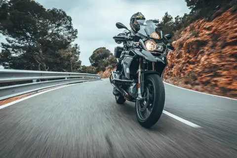 Fahrer auf einer BMW 1200 GS fährt auf einer kurvigen Bergstraße.