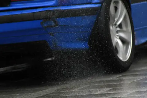 Blauer Sportwagen mit drehendem Rad, das Wasser aufwirbelt. Die elektronische Differenzialsperre sorgt für Grip.