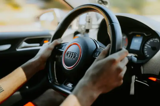 Hände am Lenkrad eines Audis, Tacho zeigt 61 km/h. Die Fahrt beginnt.