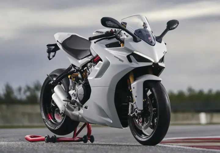 Eine weiße Ducati Supersport 950 steht auf einem roten Motorradständer. Das Motorrad hat einen sportlichen Look mit scharfen Linien und einem aerodynamischen Design.