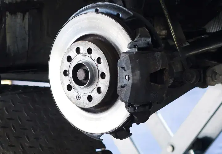 Nahaufnahme einer Bremsscheibe aus Metall, die an einem Auto montiert ist. Das Material der Bremsscheibe ist robust und für hohe Temperaturen ausgelegt.