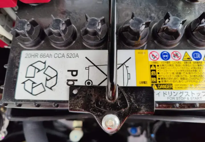 Mitsubishi Space Star Batterie wechseln: Das Bild zeigt eine Autobatterie mit Warnhinweisen und Spezifikationen wie 20HR 66Ah CCA 520A.