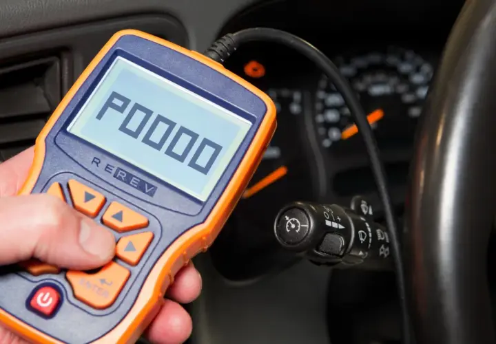 OBD-II-Diagnosegerät zeigt Fehlercode P0000 an. Ein Mann hält das Gerät in der Hand, während im Hintergrund das Armaturenbrett eines Autos zu sehen ist.