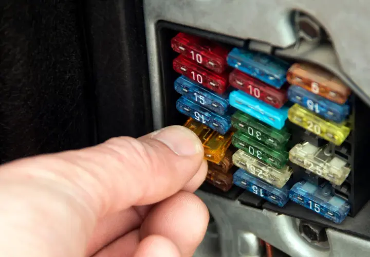 Hand prüft Sicherungen im Auto. So erkennt man eine defekte Sicherung: Der Draht im Inneren ist durchgebrannt.