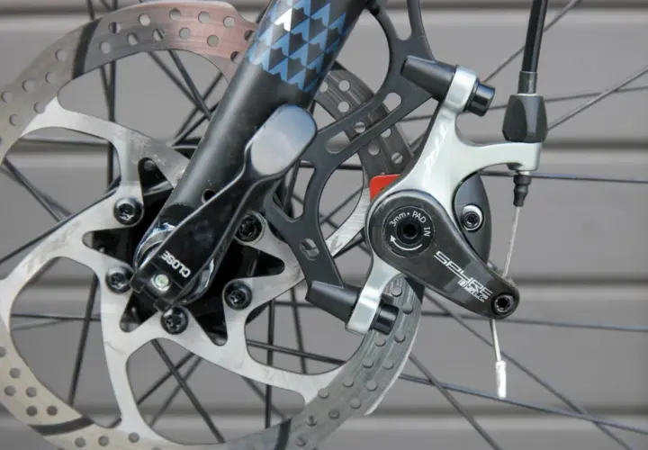Nahaufnahme einer Fahrradbremse mit verschiedenen Arten von Bremsscheiben und einem TRP Spyre-Bremssattel.