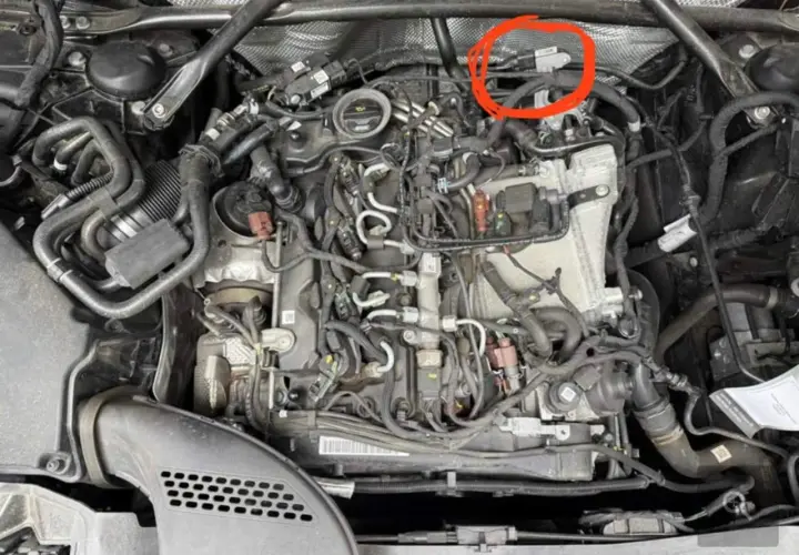 Motorraum eines Mercedes mit rotem Kreis um einen Sensor.