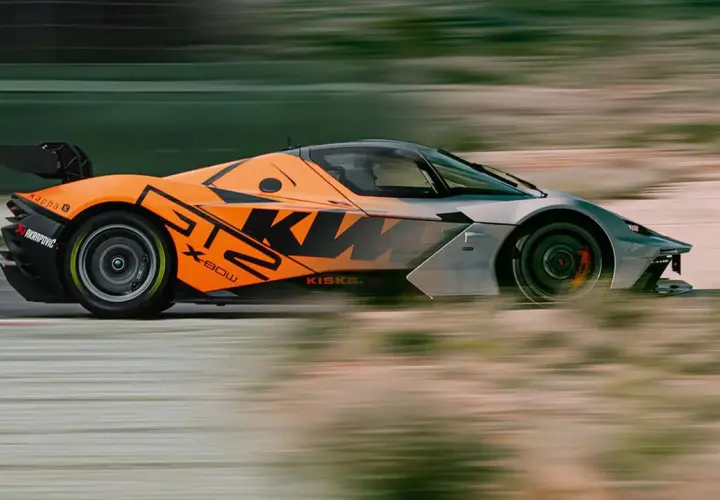 Orange-grauer KTM GT2-Sportwagen rast über die Rennstrecke, mit verschwommenem Hintergrund.