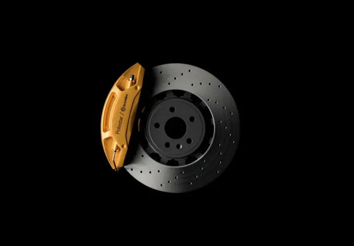 Goldener Bremssattel von Polestar/Brembo auf gelochter Bremsscheibe. So funktioniert eine Bremse: Reibung stoppt das Fahrzeug.