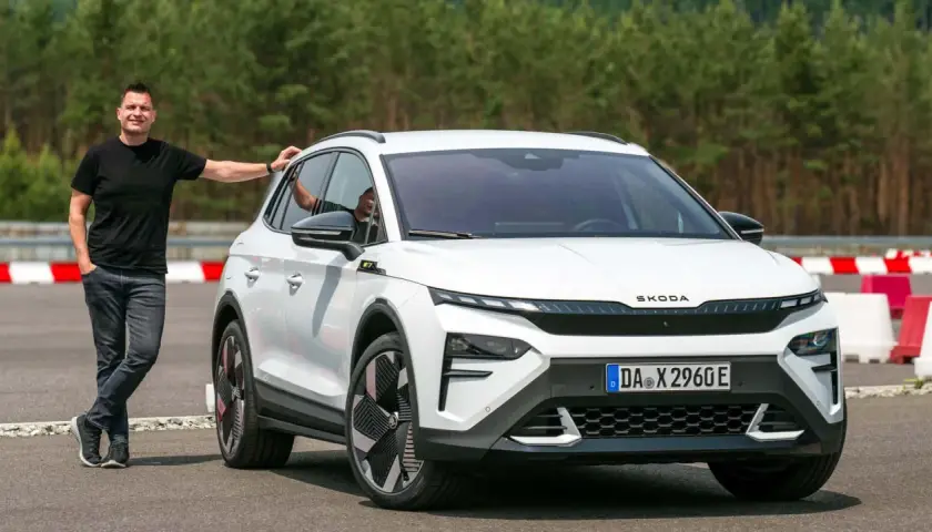Mann lehnt an weißem Skoda Enyaq RS. Was heist RS? Sportlichkeit und Leistung, die man hier sieht.