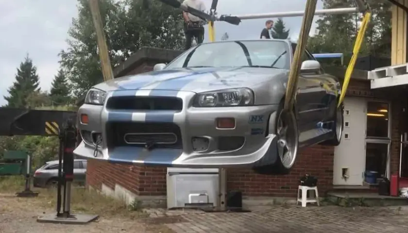 Der ikonische Paul Walker Nissan Skyline R34, bekannt aus "Fast & Furious", wird von einem Kran angehoben.