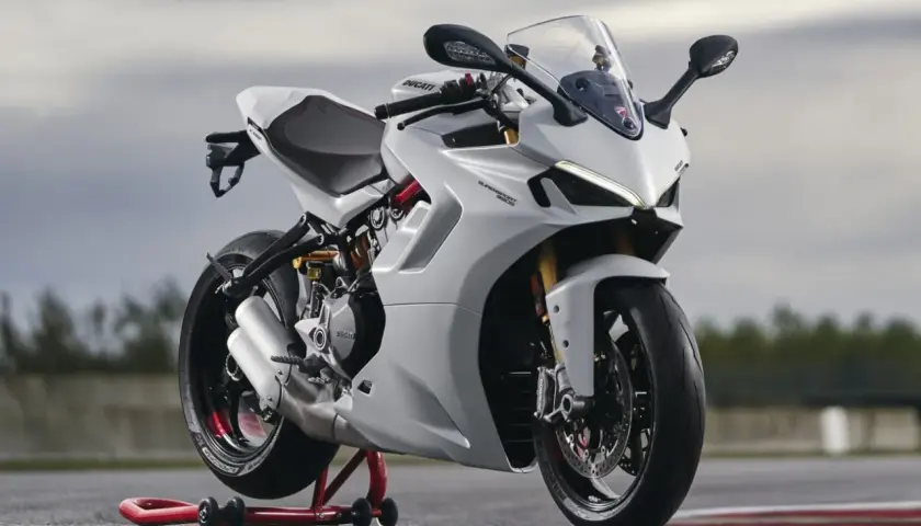 Eine weiße Ducati Supersport 950 steht auf einem roten Motorradständer. Das Motorrad hat einen sportlichen Look mit scharfen Linien und einem aerodynamischen Design.
