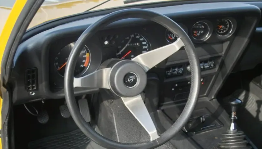 Der opel gt innenraum zeigt ein ledernes Lenkrad, klassische Rundinstrumente und einen Schaltknüppel.