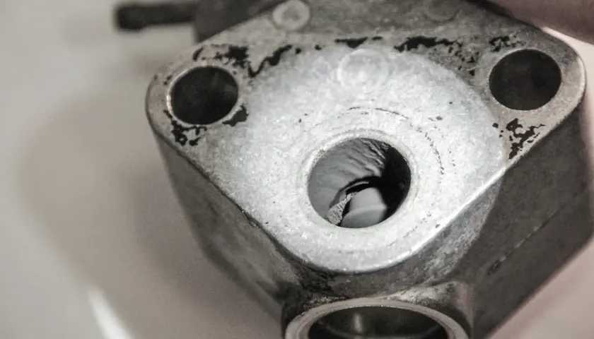 Detailaufnahme eines metallischen Bauteils, vermutlich ein p0402 vw Teil, mit sichtbaren Bohrungen und Gebrauchsspuren.