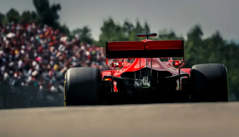 Ein roter Formel 1 Bolide rast auf die Tribüne zu. Man fragt sich, wie viel PS ein Formel 1 Auto hat, wenn es so schnell ist.