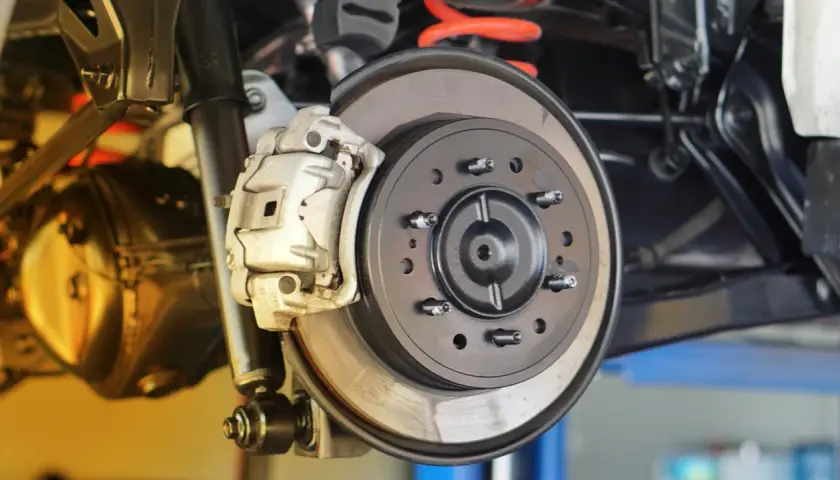 Nahaufnahme einer Autobremsanlage. Die Bremsbeläge greifen die neue Bremsscheibe. Zeit, die Bremsscheiben zu wechseln.