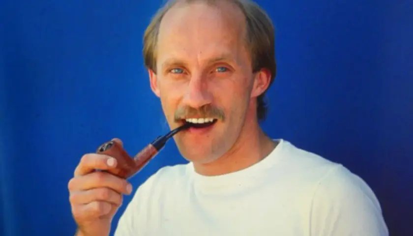 Ein Mann mit Schnurrbart, Reinhold Roth, hält eine Pfeife im Mund.
