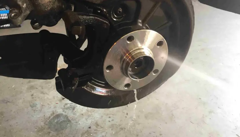 Radnabe eines Golf 5, bereit für den Wechsel des vorderen Radlagers. Flüssigkeit tropft auf den Boden.