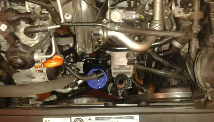 Anleitung zum Wechseln des Thermostats beim Golf 6 1.6 TDI. Motorraum mit sichtbarem Ölfilter und Kühlmittelbehälter.