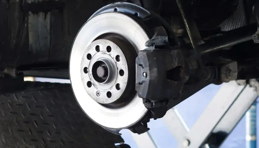 Nahaufnahme einer Bremsscheibe aus Metall, die an einem Auto montiert ist. Das Material der Bremsscheibe ist robust und für hohe Temperaturen ausgelegt.