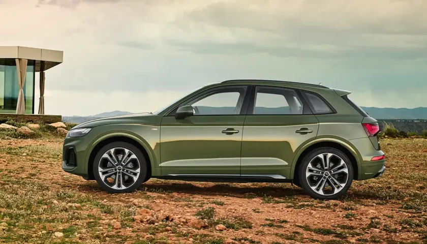 Grüner Audi Q5 mit 3,0 l V6 Diesel-Motorisierung steht auf einem felsigen Untergrund vor einem modernen Gebäude.