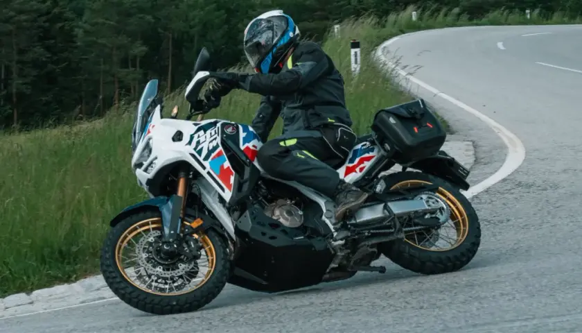 Motorradfahrer mit Helm und Ausrüstung nimmt eine Kurve, der Lenkimpuls des Motorrads ist deutlich zu sehen.