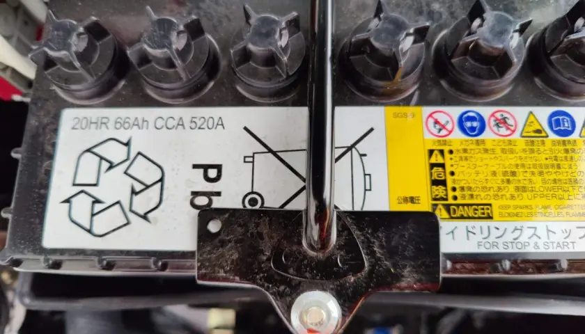 Mitsubishi Space Star Batterie wechseln: Das Bild zeigt eine Autobatterie mit Warnhinweisen und Spezifikationen wie 20HR 66Ah CCA 520A.