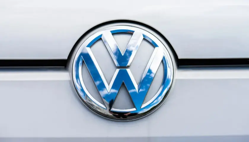 Das glänzende VW-Logo auf dem silbernen Lack reflektiert den blauen Himmel mit Wolken. Ein p0016 vw.