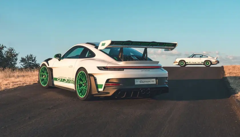 Zwei weiße Porsche 992 GT3 RS mit grünen Akzenten, einer im Vordergrund, der andere im Hintergrund, der an den Carrera RS erinnert.