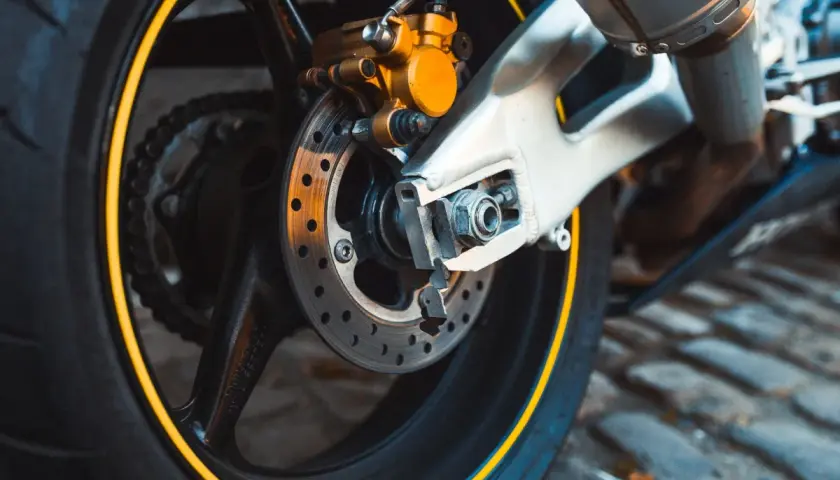 Motorradbremse mit gelbem Bremssattel. Zeit für einen neuen Bremsbelag wechseln, um sicher unterwegs zu sein.