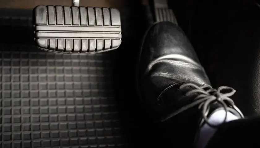Ein Schuh steht bereit, um das Bremspedal zu betätigen. So weißt du, wo ist die bremse beim auto.