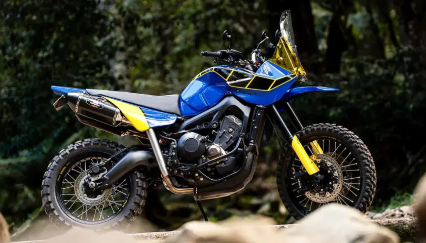 Eine blaue Yamaha Ténéré mit gelben Akzenten und Offroad-Reifen steht im Freien.