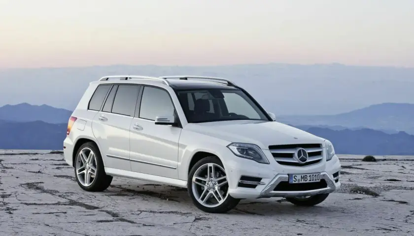 Weißer Mercedes GLK steht auf felsigem Untergrund vor bergiger Kulisse.