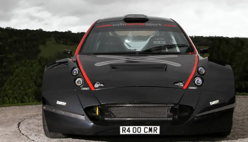 Schwarzer Rallye-Rennwagen, ein Colin McRae R4, mit roten Akzenten und dem Schriftzug "www.colinmcraesport.com" auf der Windschutzscheibe.