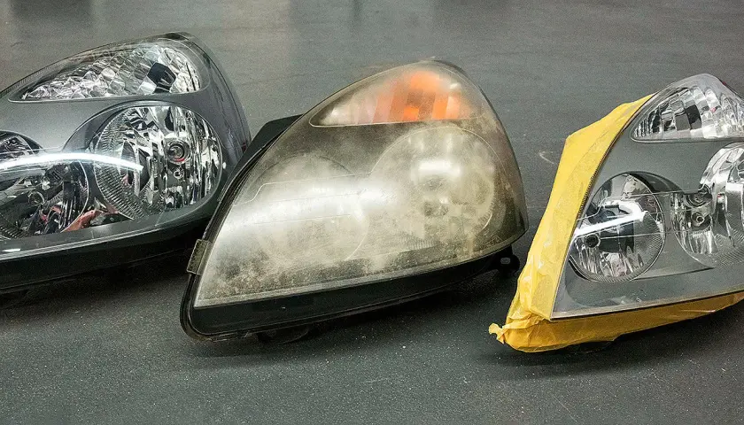 Scheinwerfer blind? Was tun? Drei Autoscheinwerfer nebeneinander: einer klar, einer trüb und einer abgeklebt.