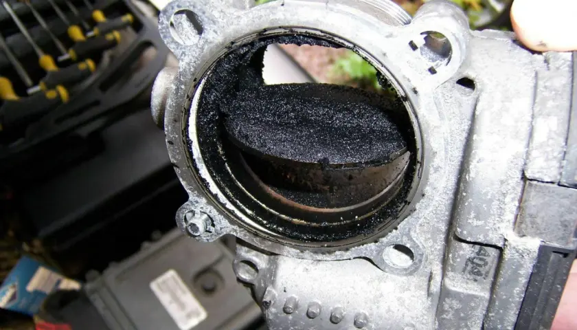 Stark verschmutztes AGR-Ventil eines Volvo XC60, bereit zum Ausbau. Rußablagerungen blockieren den Durchgang.